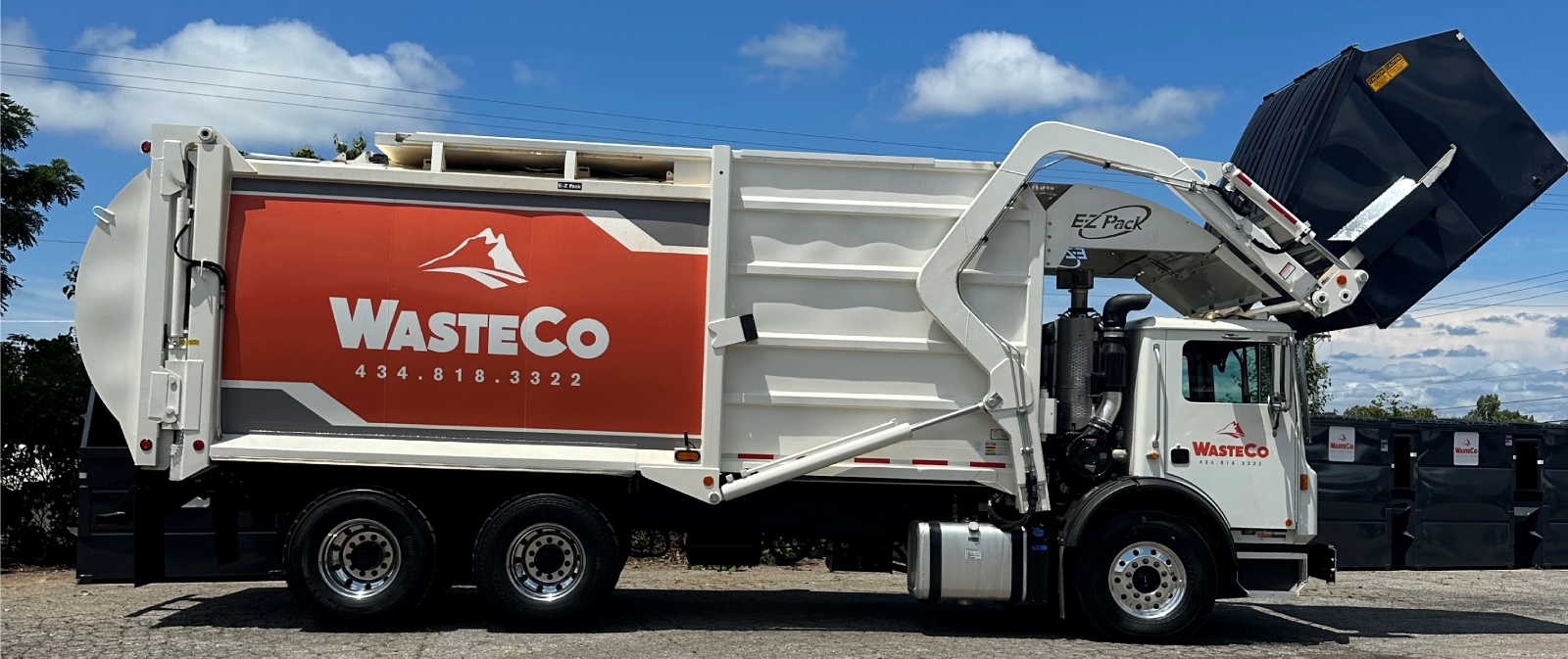 wasteco dump truck picking up front load dumpster